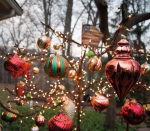 Ornaments and lights hang from an iron tree that sits outside the screened porch.