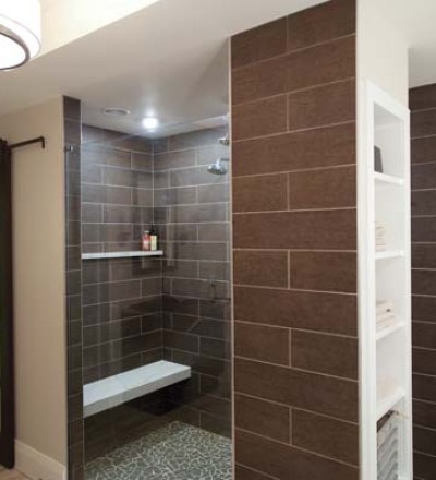 The bronze tile that comprises the walk-in shower has a wood-like texture. The tower provides added storage for towels. Note the custom glass/wood sliding door that provides access to the water closet.