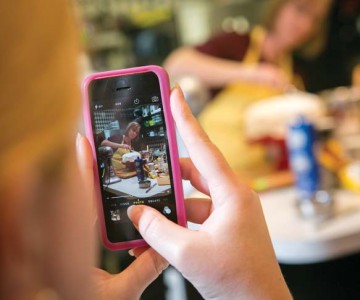 A student takes a photo of chef Tina Bare in the kitchen.