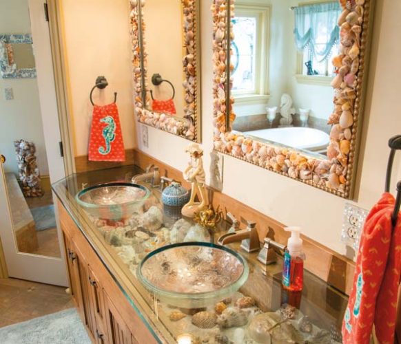 Jim Schopf, Andrea’s husband, designed the double vanity. The board over the cabinet doors flips down, allowing Andrea to switch shells in and out of the sand-covered shelf. Andrea created the shell-embellished mirrors.