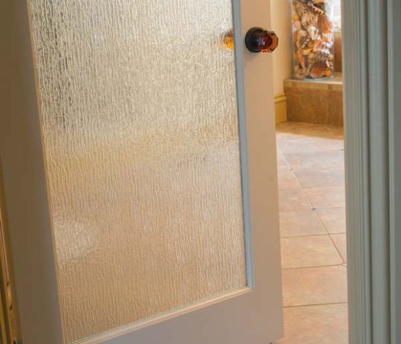 The glass door that provides access to the master bath mimics rain water.