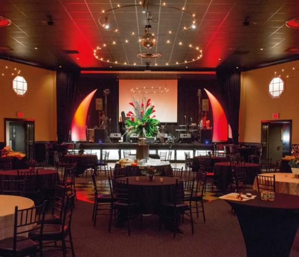 As a nod to Dave’s career as special events manager for the Chicago Bulls, the stage was flanked with huge, inflatable red horns. The Hamilton Ballroom’s neutral walls were enlivened by uplights, washing the room in vibrant red. Bold arrangements of tropical flowers completed the decor.